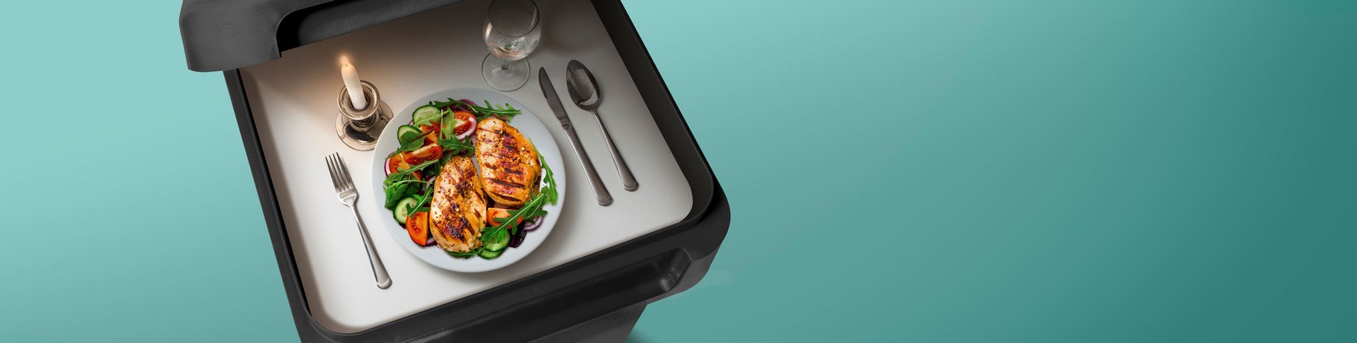 Eine Speise mit Salat auf einem Tablett und einer Kerze angerichtet.